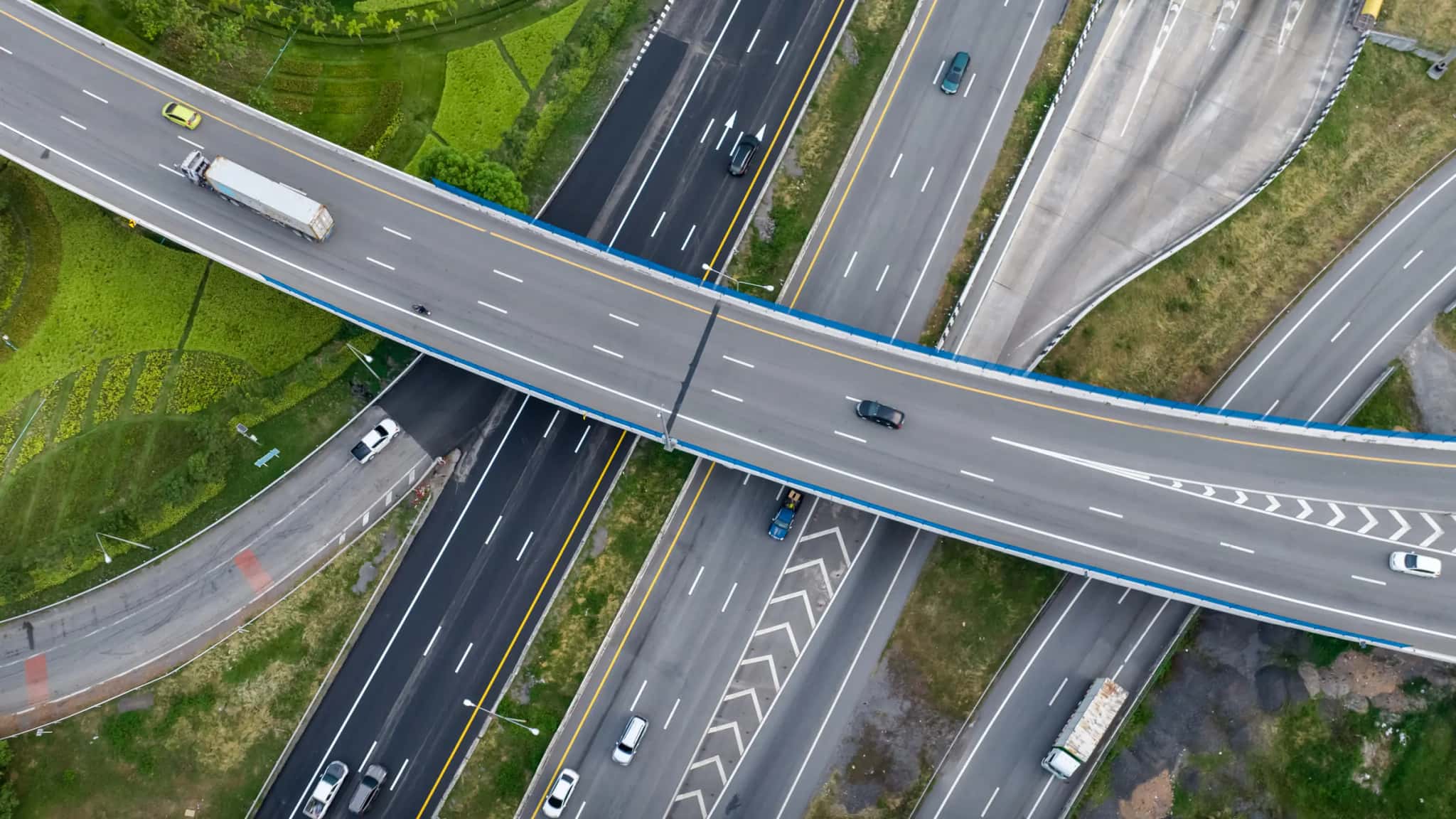 Aerial view of a highway interchange with trucks and cars, surrounded by greenery